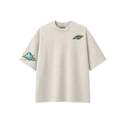 Front view of the Time Spiral oversized graphic t-shirt in off-white, featuring an original hand-drawn eye artwork on the chest and a cloud illustration on the sleeve. Made from 100% premium cotton and designed by Uniart.