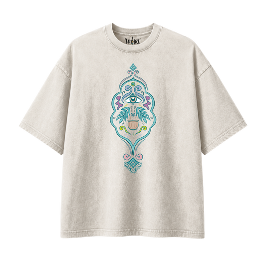 A light beige mineral-wash t-shirt with a central graphic of a stylized eye surrounded by teal, purple, and pink ornate patterns, shown on a plain white background.